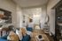 Elegant living room with modern decor, featuring a cozy blue sofa, stylishly accented cushions, and a sleek open kitchen with chic pendant lighting.