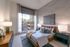 Elegant bedroom with chic decor, large window offering city views, and modern furnishings.