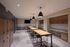 Modern communal area with sleek wooden tables, stylish pendant lighting, and integrated workstations, perfect for collaborative work and social gatherings.