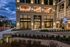 Elegant apartment entrance at dusk with stylish architecture, featuring expansive glass windows and modern lighting.