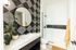 Model bathroom featuring a round mirror and modern finishes