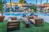 Luxurious outdoor seating area with cozy fire pit and poolside view, surrounded by lush greenery and elegant architecture.