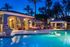 Luxurious evening poolside view with elegant architecture, cozy lounge chairs, and ambient lighting under palm trees.