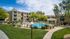 Beautiful apartment complex with lush greenery and a sparkling pool surrounded by modern three-story buildings, offering a serene and inviting living environment.