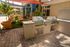 Luxurious outdoor area featuring modern stainless steel grills, cozy seating with lush greenery, and shaded spaces, perfect for entertaining by the pool.