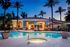 Luxurious modern apartment complex featuring an inviting swimming pool, elegant lounge area, and lush palm trees at sunset.