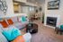 Inviting living room with plush gray sofa and vibrant pillows, featuring modern decor, a cozy fireplace, and an elegant dining area.