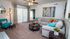 Inviting living room featuring a cozy beige sectional sofa, vibrant accent chairs, and elegant decor with natural light streaming through vertical blinds.