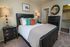 Charming bedroom with elegant decor, featuring a plush bed with colorful pillows, stylish nightstands, and a spacious walk-in closet.