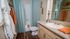 Inviting bathroom with elegant granite countertop, soothing blue shower curtain, and vibrant orange accents for a pop of color.