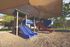 Inviting playground with vibrant slides and climbing structures under a sunshade, surrounded by lush greenery.