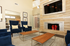 Elegant living room with plush blue chairs, modern fireplace, and stylish wooden coffee tables, perfect for luxurious relaxation.