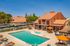 Charming residential complex featuring a refreshing swimming pool with vibrant orange umbrellas and cozy outdoor seating, surrounded by picturesque architecture and lush greenery, perfect for relaxation and leisure.