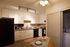 Modern kitchen with sleek countertops, elegant white cabinetry, and convenient in-unit laundry.