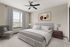 Elegant bedroom featuring a plush king-size bed, modern artwork, and a cozy reading chair, bathed in natural light from large windows with stylish curtains.