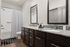 Modern bathroom with elegant granite countertop, dual sinks, and stylish mirrors, featuring a sleek bathtub and rich wood cabinetry.