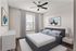 Inviting bedroom showcasing a modern bed with chic linens, elegant artwork, and natural light flooding through large windows.