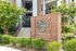 Impressive entrance to luxury apartment complex, with modern architectural details and lush greenery.