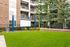 Charming apartment courtyard featuring a vibrant green lawn, cozy seating area, and outdoor movie screen, perfect for relaxing and social gatherings.