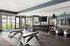 Spacious modern gym featuring state-of-the-art equipment, ample natural light, and mirrored walls for an enhanced workout experience.