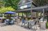 Charming outdoor patio with modern pergola, cozy fireplace, and elegant dining furniture in a lush garden setting.