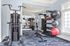Modern gym space with state-of-the-art equipment, featuring weight racks, exercise balls, and a multi-functional workout machine against a bright windowed wall.