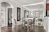 Elegant dining area with a glass table and stylish chairs, featuring contemporary wall art and a well-lit mirrored wall for enhanced ambiance.