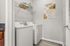 Contemporary laundry room featuring a modern washer and dryer set, open shelving with stylish storage solutions, and abstract wall art for a touch of elegance.