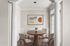 Elegant dining area with modern furniture, featuring a round wooden table and four stylish chairs, enhanced by contemporary artwork and natural lighting.