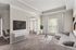 Elegant living room with modern decor, featuring a sleek gray sectional, large flat-screen TV, and abundant natural light through expansive windows.