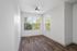 Bright and airy room with elegant wood flooring, large windows, and a modern ceiling fan, perfect for a cozy home setting.