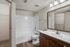 Modern bathroom with sleek wooden cabinets, elegant lighting, and spacious white tub offering a tranquil retreat.