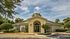 Charming community welcome center with inviting architecture, lush landscaping, and a bright entrance, perfect for a warm and friendly residential atmosphere.