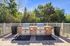 Charming outdoor patio with dual stone barbecue grills surrounded by lush greenery, perfect for social gatherings.