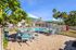 Charming outdoor pool area with stylish patio seating and refreshing palm trees under bright blue skies.