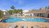 Inviting apartment complex with a sparkling pool, surrounded by lush palm trees and comfortable lounge chairs, perfect for a tropical retreat.