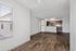 Modern apartment interior showcasing an open floor concept with sleek hardwood floors, a stylish kitchen featuring wood cabinetry and stainless steel appliances, and abundant natural light from large windows.