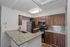 Modern kitchen with granite countertops, stainless steel appliances, and dark wood cabinetry, featuring a chic tile backsplash and ambient lighting.