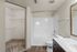 Modern bathroom with sleek white tiles, a spacious bathtub, and an adjoining walk-in closet with ample shelving.
