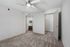 Inviting bedroom showcasing plush carpet and modern ceiling fan, leading to a well-appointed bathroom with stylish cabinetry.