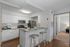 Modern kitchen with sleek stainless steel appliances, granite countertops, and stylish bar seating, leading to a cozy living space.
