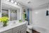 Bright and modern bathroom featuring elegant white cabinetry, vibrant blue and green accents, and a luxurious bathtub. Fresh flowers add a touch of nature and style.