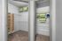 Spacious walk-in closet with ample shelving and storage solutions, featuring neatly arranged green and white striped baskets.