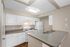 Modern kitchen with sleek white cabinets, stainless steel sink, and gas stove, offering a bright and inviting cooking space.