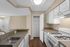 Charming kitchen with sleek countertops, white cabinetry, and a cozy pantry. Ample lighting enhances the warm atmosphere, perfect for culinary creativity.
