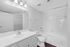 Pristine bathroom showcasing modern white fixtures, sleek cabinetry, and a clean, bright aesthetic with stylish lighting.