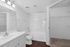 Bright and modern bathroom featuring a sleek white vanity, spacious tub, and luxury wood-look flooring.