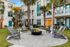 Inviting apartment courtyard featuring Adirondack chairs around a central fire pit, surrounded by palm trees.