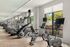 Modern gym with advanced exercise machines and large windows.