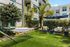 Inviting outdoor garden space with a hammock, plush seating, and tropical greenery at a modern apartment complex.
